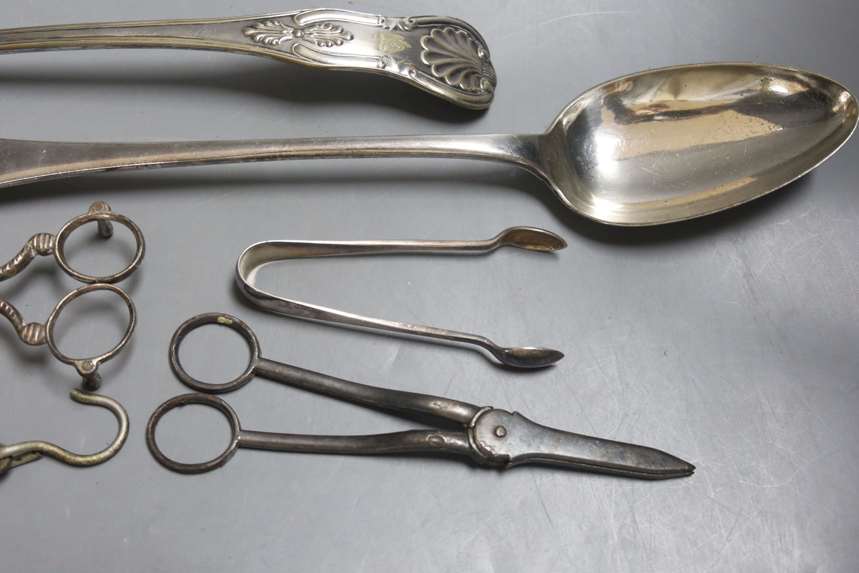 A large plated ladle and basting spoon, two candle snuffers, tongs and spring balance